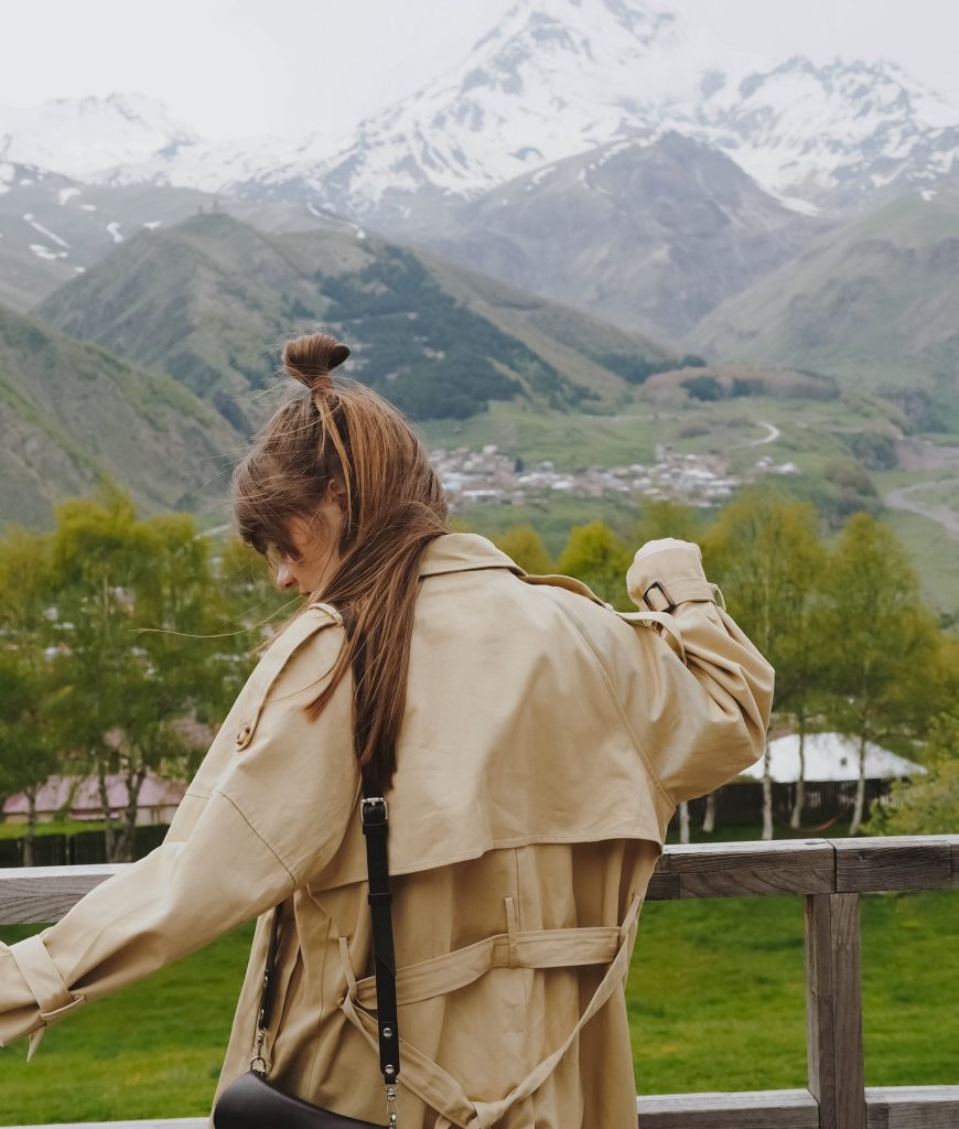Free girl stands and admires the view of the Kazbegi mountains in Georgia